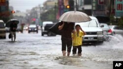 Warga setempat berjalan melewati banjir akibat hantaman badai tropis Kong-Rey di Tainan, Taiwan, Kamis (29/8).