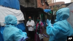 Health workers screen people for COVID-19 symptoms at a slum in Mumbai, India, July 14, 2020. 