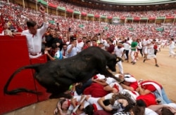 A wild cow jumps over revelers after the last bull run of the San Fermin festival in Pamplona, Spain, July 14, 2019.