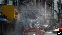 Members of Fire Service Department wearing full protective gear spray disinfectant from the fire vehicle to stop the spread of the coronavirus on a street in Yangon, Myanmar.