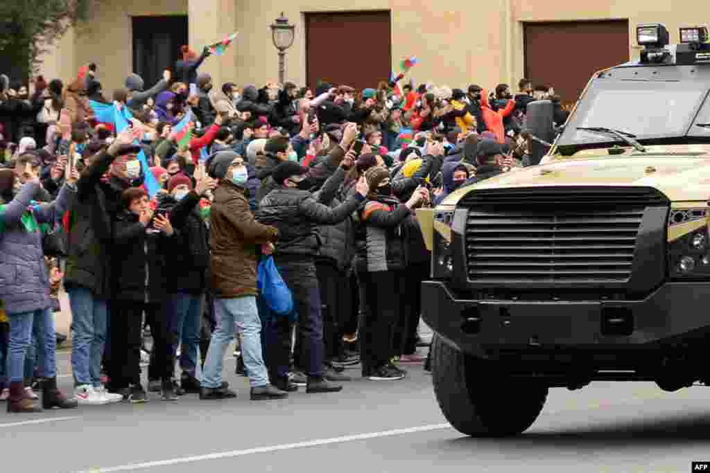 People greet Azerbaijani servicemen riding in military vehicles during a parade marking Azerbaijan's victory against Armenia in their conflict for control over the disputed Nagorno-Karabakh region, in Baku.