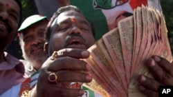 An activist of Congress party holds banned 500 and 1000 rupee notes during a protest against the government's decision to take high denomination notes from circulation, in front of Reserve Bank of India. in Hyderabad, Nov. 28, 2016. 