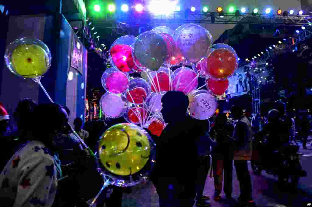 A vendor sells balloons on a decorated street on the Christmas Eve in Kolkata, India.