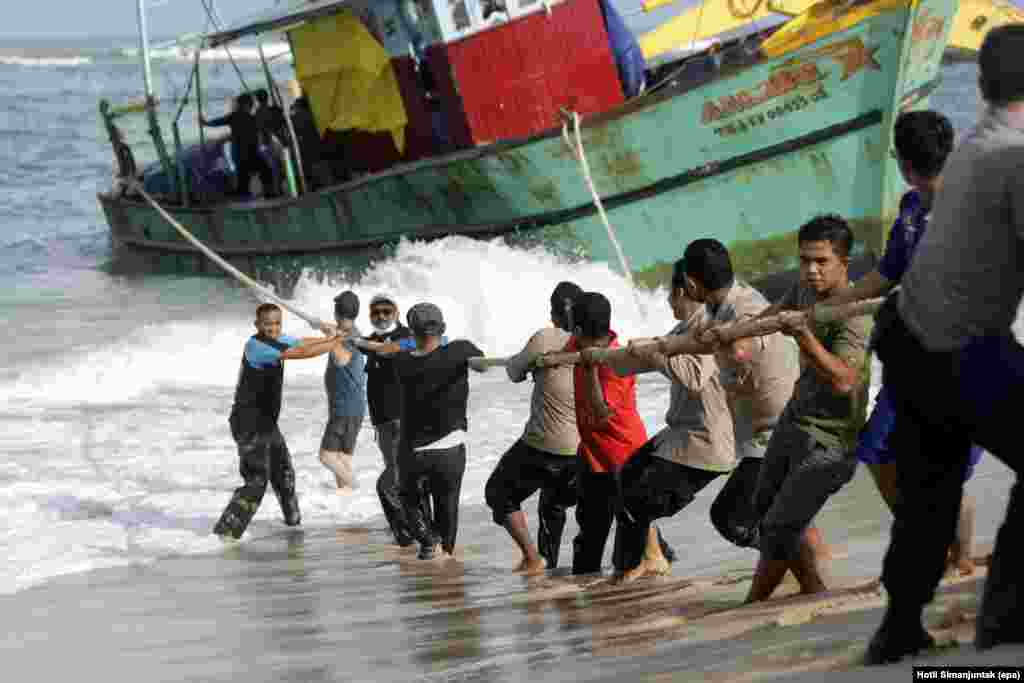 Indonesian security personnel pull a stranded Sri Lankan boat before it is towed into the open sea, at Lhoknga beach in Aceh Province. Nearly 44 migrants from Sri Lanka drifted into Aceh waters after their boat's engine failed on June 17.