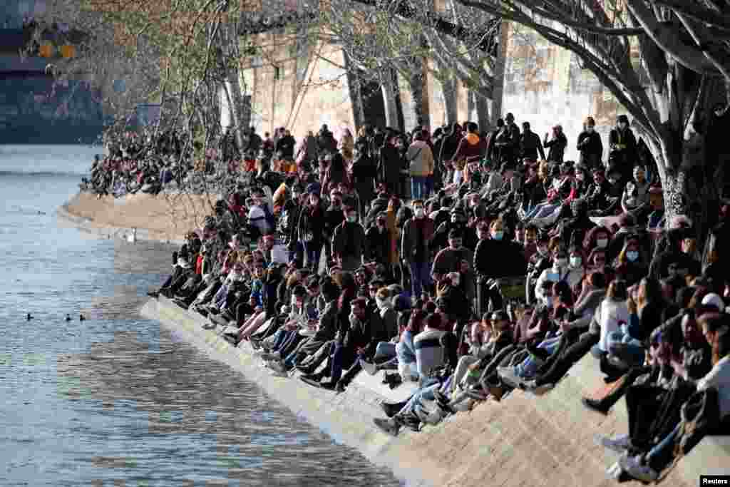 People sit along the Seine river, enjoying the weather during the COVID-19 outbreak, in Paris, France.