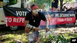 Josh Sly of the Muggera Dancers prepares a fire for a smoking ceremony at the start of an Invasion Day rally in Sydney, Jan. 26, 2023.