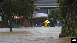 Emergency workers and a man wade through floodwaters in Auckland, New Zealand, Jan. 27, 2023. Torrential rain and wild weather in Auckland caused disruptions throughout the city.