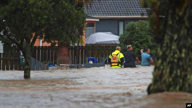 Emergency workers and a man wade through floodwaters in Auckland, New Zealand, Jan. 27, 2023. Torrential rain and wild weather in Auckland caused disruptions throughout the city.