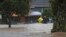 Emergency workers and a man wade through floodwaters in Auckland, New Zealand, Jan. 27, 2023. Torrential rain and wild weather in Auckland caused disruptions throughout the city.