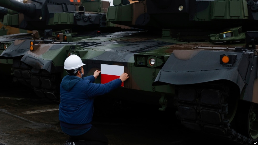 Seorang petugas memasang bendera Polandia di tank Black Panther K2 Korea Selatan di pelabuhan Angkatan Laut Polandia Gdynia, Polandia, 6 Desember 2022. (AP/Michal Dyjuk)