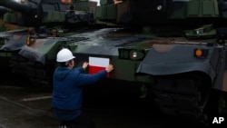 Seorang petugas memasang bendera Polandia di tank Black Panther K2 Korea Selatan di pelabuhan Angkatan Laut Polandia Gdynia, Polandia, 6 Desember 2022. (AP/Michal Dyjuk)