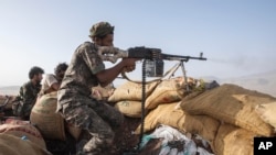 FILE - A Yemeni fighter backed by the Saudi-led coalition fires his weapon during clashes with Houthi rebels near Marib, Yemen, June 20, 2021. Omani mediators arrived in Yemen on Saturday to discuss a new truce between Houthi rebels and Saudi Arabia, a source said.