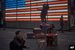 People spend time in Times Square on Tuesday, Jan. 17, 2023, in New York. (AP Photo/Andres Kudacki)