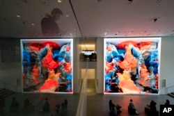 Visitors view artist Refik Anadol's "Unsupervised" exhibit at the Museum of Modern Art, Wednesday, Jan. 11, 2023, in New York. The new AI-generated installation is meant to be a thought-provoking interpretation of the New York City museum's prestigious collection. (AP Photo/John Minchillo)
