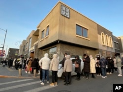 Customers wait in a line in cold weather outside Daoxiangcun to buy new year gift boxes on Jan. 14, 2023. (AP Photo/Caroline Chen)