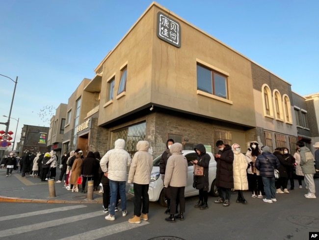 Customers wait in a line in cold weather outside Daoxiangcun to buy new year gift boxes on Jan. 14, 2023. (AP Photo/Caroline Chen)