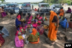 FILE - Former 'devadasis' women eat near a pond used by 'devadasis' women to cleanse themselves before visiting Yellamma Devi temple in Savadatti of Belgaum district, in India's Karnataka state, Sept. 21, 2022.