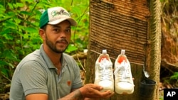 Rubber tapper Rogerio Mendes shows off his Veja sneakers, received as a prize for his work as a young rubber extractor in the Chico Mendes Extractive Reserve, Acre state, Brazil, Dec. 7, 2022. 