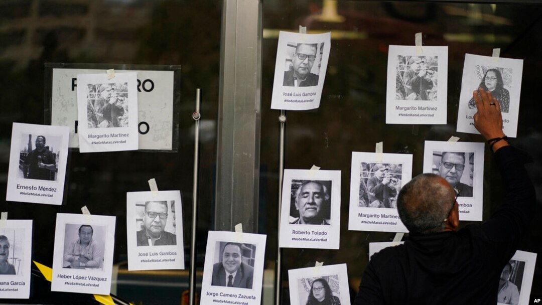 Seorang pria memasang foto pewarta yang terbunuh di luar kantor Kejaksaan Agung Meksiko di Mexico City, 24 Agustus 2022. (Foto: AP)