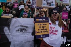 Perawat memegang spanduk dan plakat dalam aksi mogok di luar Royal College of Nursing, London, Rabu, 18 Januari 2023. (AP/Kin Cheung)