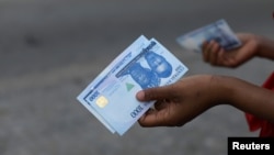 FILE - A person holds a new 1000 naira note as the Central Bank of Nigeria releases the notes to the public through the banks in Abuja, Nigeria, Dec. 15, 2022.
