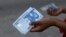 FILE - A person holds a new 1,000 naira note as the Central Bank of Nigeria releases the notes to the public through the banks in Abuja, Nigeria, Dec. 15, 2022.
