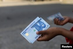 FILE - A person holds a new 1,000 naira note as the Central Bank of Nigeria releases the notes to the public through the banks in Abuja, Nigeria, Dec. 15, 2022.