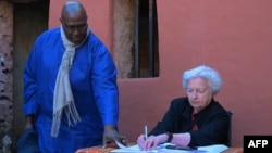 US Treasury Secretary Janet Yellen, flanked by curator Eloi Coly (L), signs the guestbook of the House of Slaves during a visit on Goree Island off the coast of the city of Dakar on January 21, 2023. 