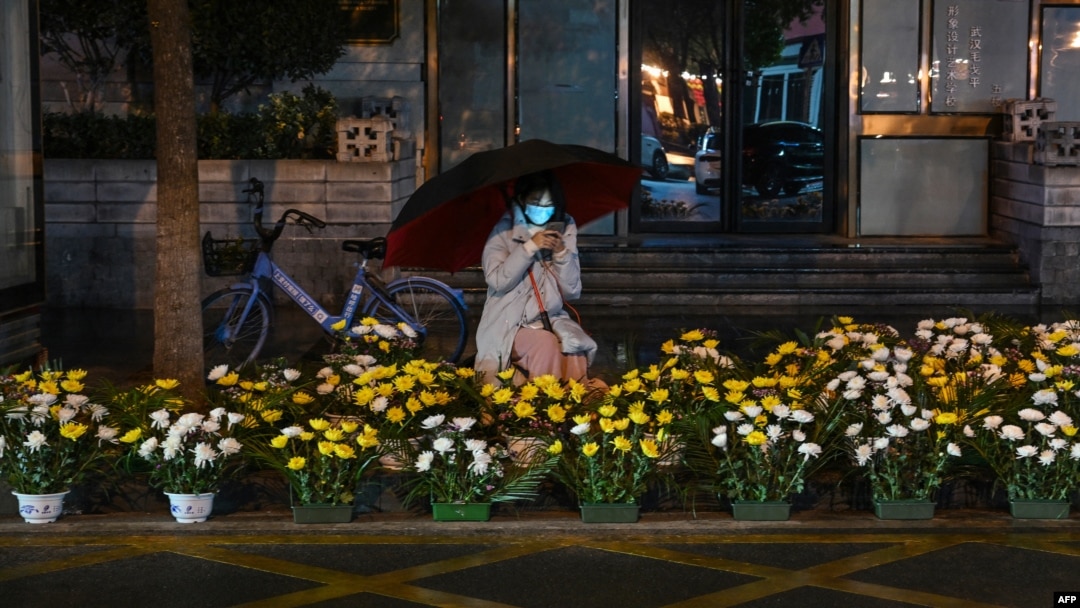 A woman selling flowers along a street waits for customers on the eve of the Lunar New Year in Wuhan, in China's central Hubei province on Jan. 21, 2023.
