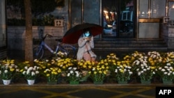 A woman selling flowers along a street waits for customers on the eve of the Lunar New Year in Wuhan, in China's central Hubei province on Jan. 21, 2023.