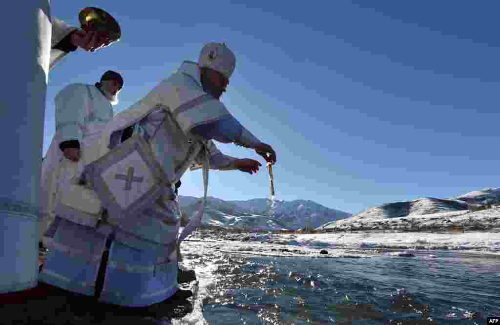An Orthodox priest blesses the water of the Kara-Balta river during the celebration of the Epiphany holiday near the village of Sosnovka, Kyrgyzstan.