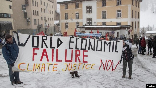 Climate activists display a banner during a protest ahead of the World Economic Forum (WEF) 2023 in the Alpine resort of Davos, Switzerland, Jan. 5, 2023.