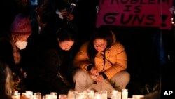 Women place candles at a memorial during a vigil blocks from the Star Ballroom Dance Studio, Jan. 24, 2023, in Monterey Park, Calif., where a gunman killed multiple people amid Lunar New Years celebrations in the predominantly Asian American community.