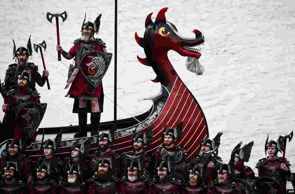 Членовите на Up Helly Aa &#39;Jarl Squad&#39; позираат со нивниот брод од галијата Викинзи во Лервик, Шетландските Острови.