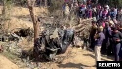 People gather around the debris of a crashed aircraft in Bharatpur, Rajasthan, India, January 28, 2023 in this screen grab obtained from a handout video. ANI/Handout via REUTERS.
