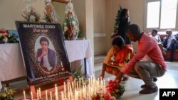 Des personnes en deuil déposent des bougies dans une salle de Radio Amplitude FM où un portrait du journaliste Martinez Zogo a été placé pour lui rendre hommage, dans le quartier Elig Essono à Yaoundé le 23 janvier 2023. 