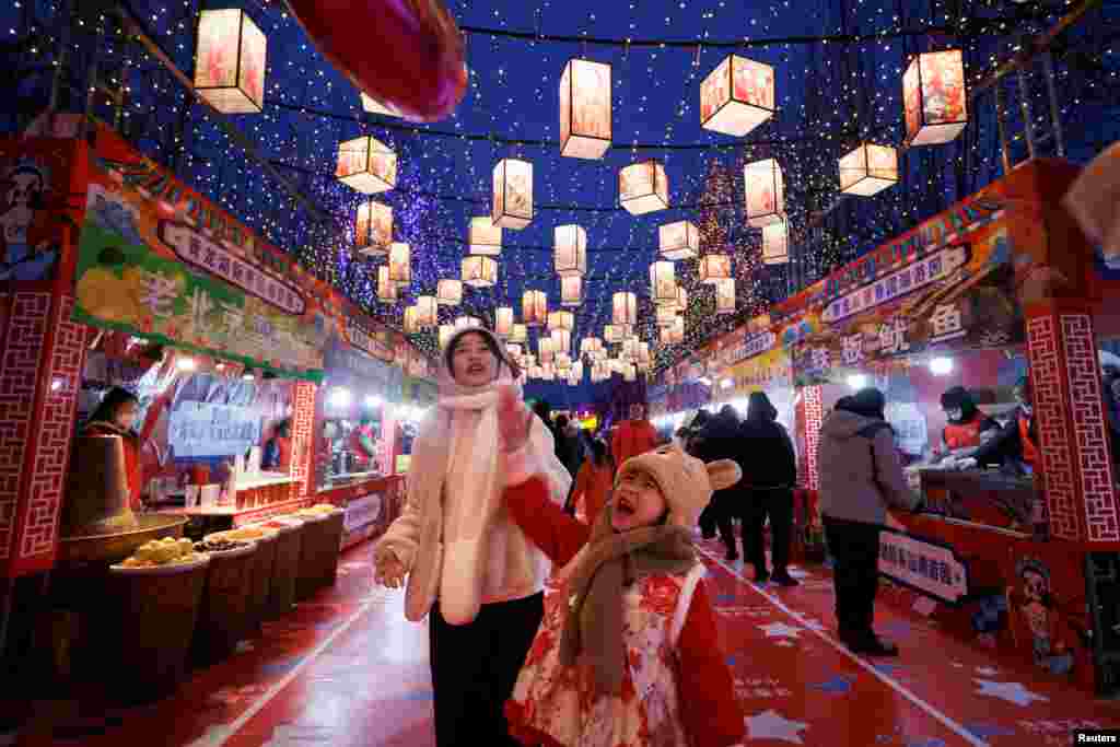 Луѓето шетаат низ украсениот терен за храна што е дел од светлосната инсталација на Пролетниот фестивал пред кинеската Лунарна Нова Година во паркот Кинглонху во Пекинг, Кина, 21 јануари 2023 година.