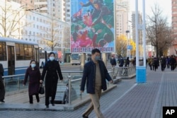 FILE - People wearing face masks walk on a street along the Pyongyang Railway Station in Central District of of Pyongyang, North Korea, Nov. 4, 2022.