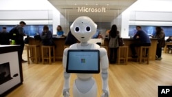 In this Sunday, March 21, 2019 photo a robot called "Pepper" is positioned near an entrance to a Microsoft Store location, in Boston. (AP Photo/Steven Senne)