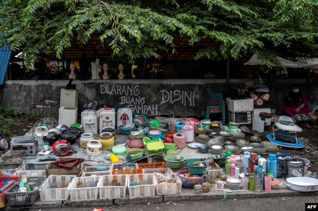 Seorang pedagang (kanan) menjual peralatan dapur bekas menunggu pelanggan di pasar barang bekas di Surabaya, 1 Februari 2023. (JUNI KRISWANTO/AFP)