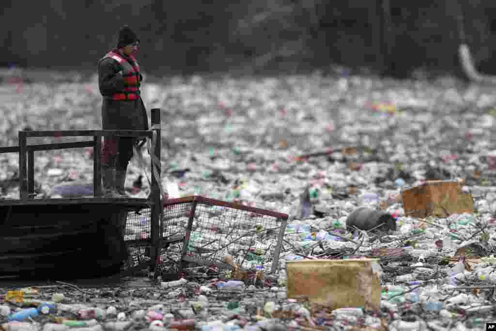 A utility company worker attempts to push the waste to the shore of the Lim River near Priboj, Serbia, Jan. 30, 2023.