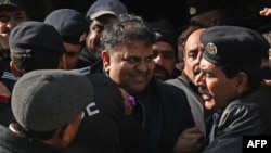 Petugas polisi mengawal mantan menteri informasi Pakistan Fawad Chaudhry (tengah) saat mereka meninggalkan pengadilan setelah sidang di Islamabad pada 27 Januari 2023. (Foto: AFP)