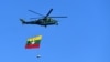 A Myanmar military helicopter carries the national flag over a parade ground to mark the country's Independence Day in Naypyidaw on Jan. 4, 2023.