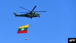 A Myanmar military helicopter carries the national flag over a parade ground to mark the country's Independence Day in Naypyidaw on Jan. 4, 2023.