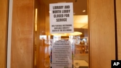 Sejumlah tanda dipasang di pintu perpustakaan di Englewood, Colorado, yang menandakan bahwa perpustakaan itu ditutup akibat kontaminasi methamphetamine pada 12 Januari 2022. (Foto: AP/David Zalubowski) 