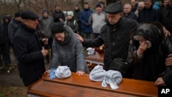 Los familiares de Maksym y Nataliia Shvets, una pareja que murió bajo los escombros después de que Rusia bombardeara su bloque de apartamentos con un misil, lloran cerca de uno de los ataúdes durante un funeral en Dnipro, Ucrania, el 18 de enero de 2023.