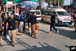 Petugas polisi membuka jalan bagi ambulans yang membawa korban terluka di lokasi ledakan bom, di Peshawar, Pakistan, Senin, 30 Januari 2023 (Foto: AP)