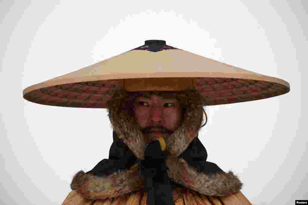 An employee in Korean traditional costume works as it snows on a cold winter day at Gyeongbokgung Palace in Seoul, South Korea.