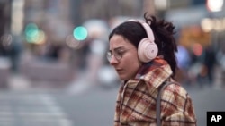 A woman walks using her headphones on Tuesday, Jan. 17, 2023, in New York. (AP Photo/Andres Kudacki)