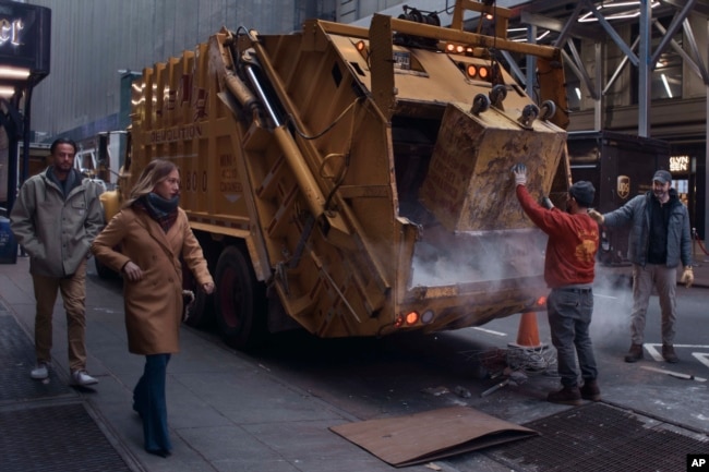 Construction workers dispose material as a couple passes by on Tuesday, Jan. 17, 2023, in New York. (AP Photo/Andres Kudacki)